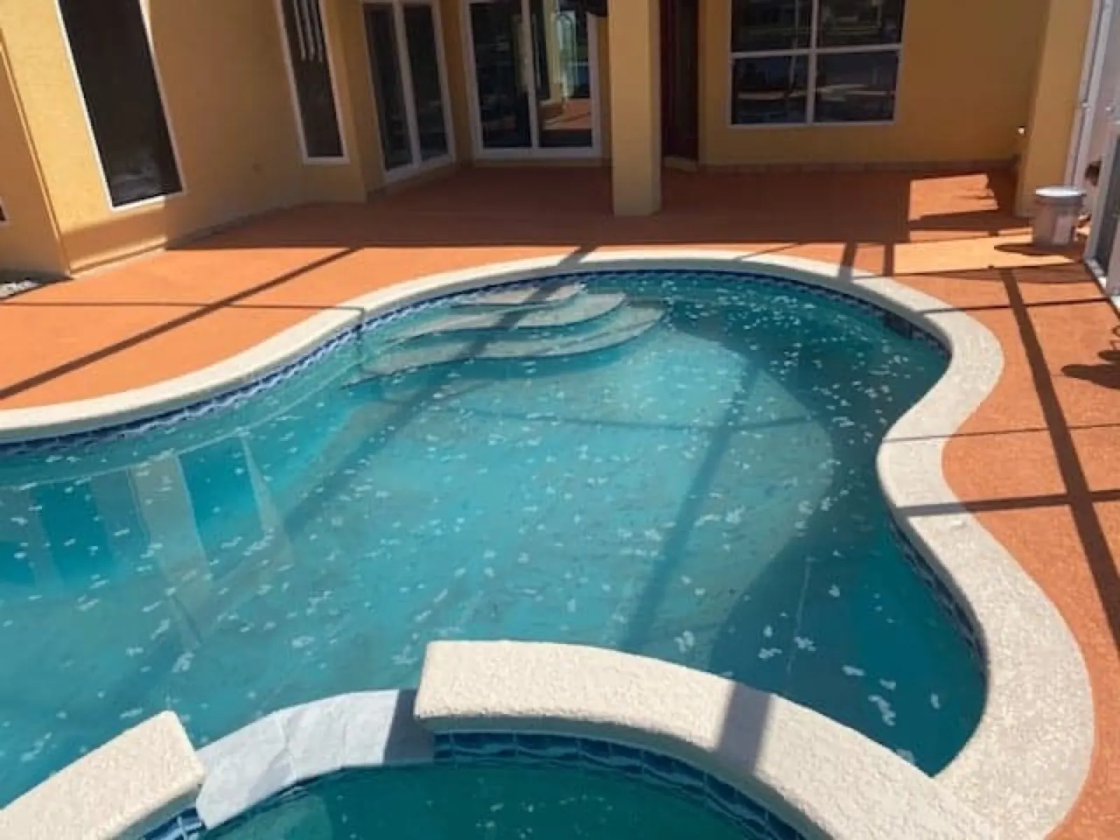 Resurfaced terracotta pool deck around a screened Florida pool